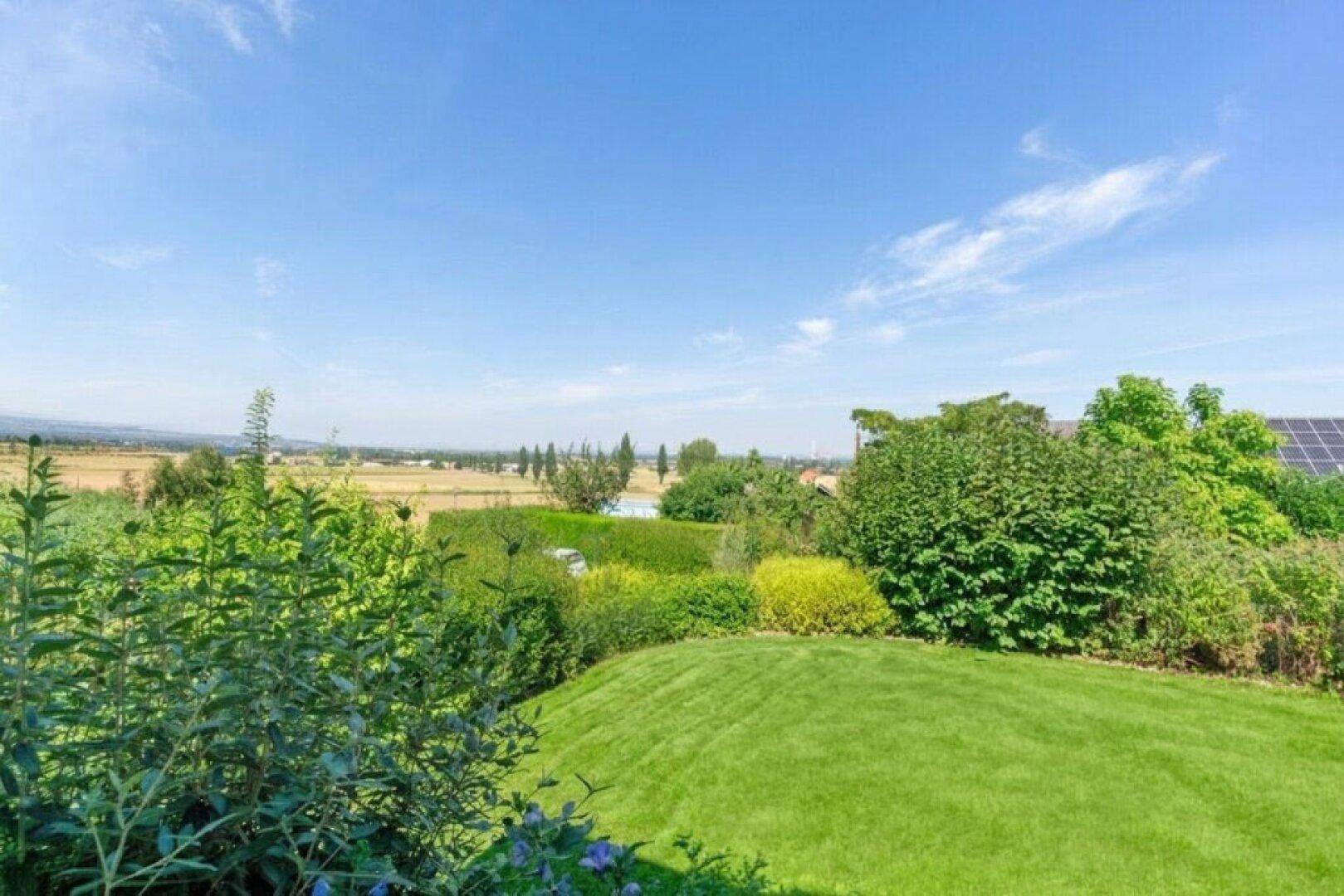 Weitläufiger Gartenbereich mit üppigem Grün und einem malerischen Blick auf die umliegende Landschaft.