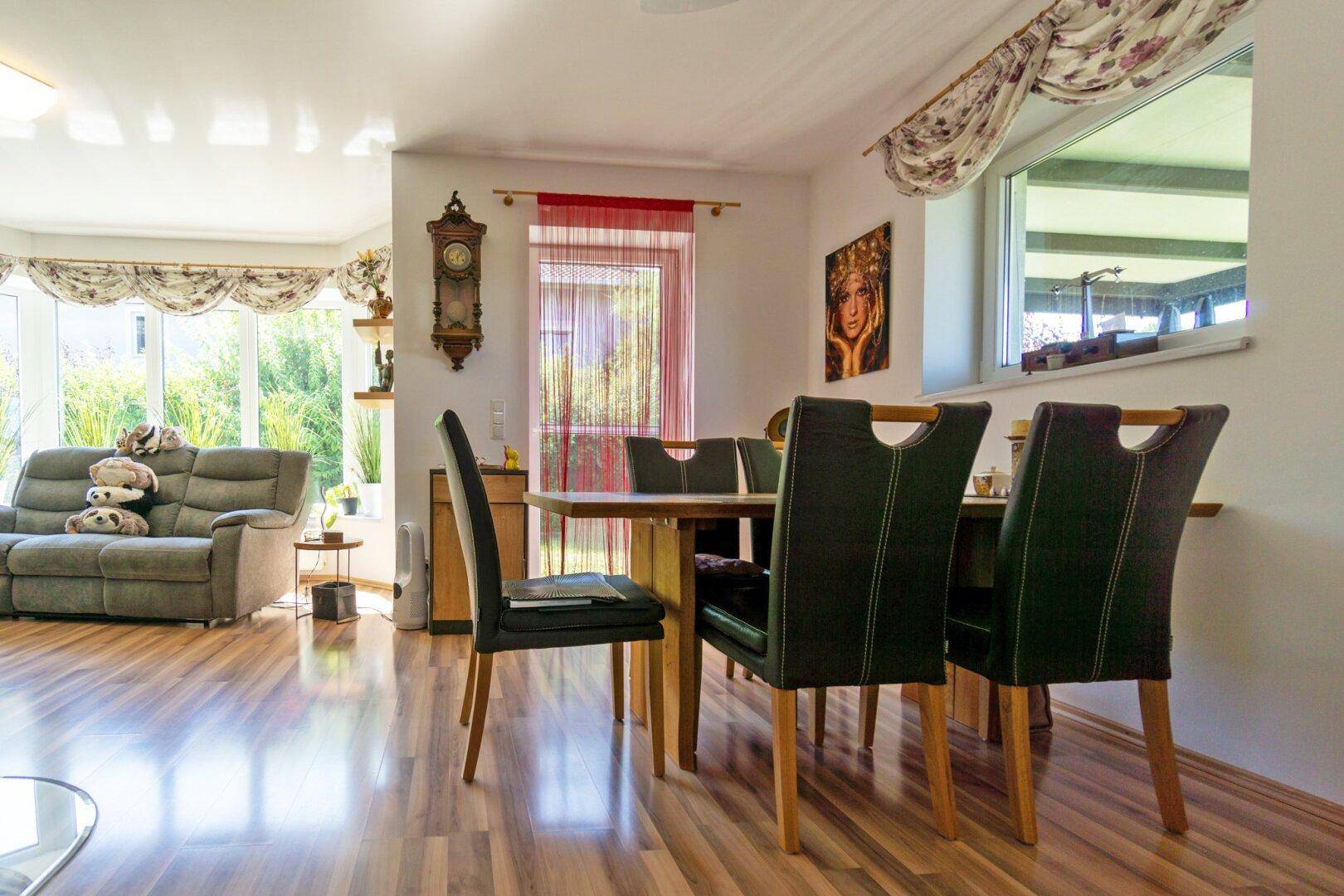 Heller Wohn-Essbereich mit Laminatboden, großem Esstisch und Blick in den Garten.