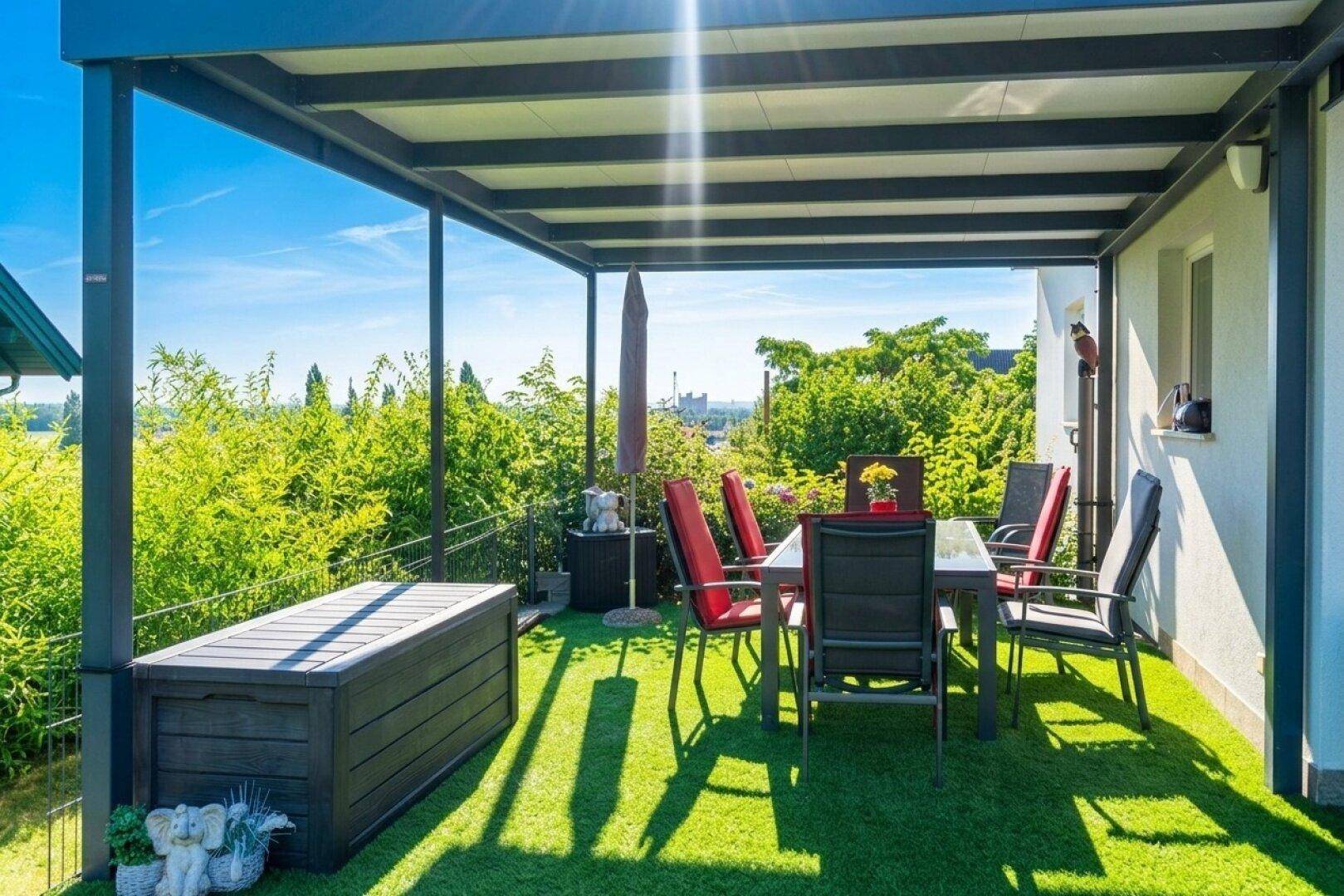 Überdachte Terrasse mit Gartenmöbeln und weitem Blick über die Landschaft.