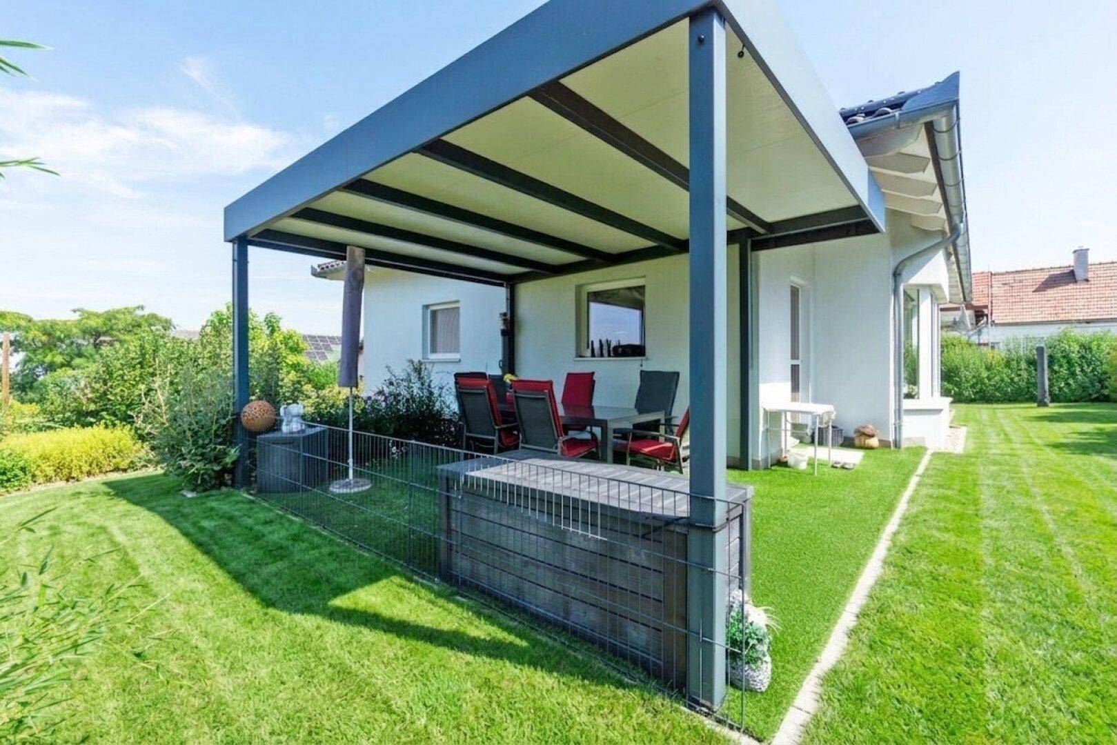 Überdachte Terrasse mit Kunstrasen und angrenzendem Gartenbereich, ideal für Entspannung im Freien.