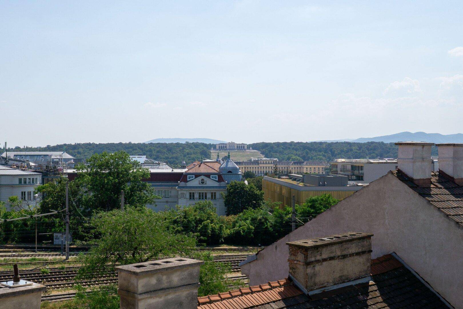 Weitläufiger Blick über die Dächer der Stadt mit grünen Hügeln im Hintergrund.