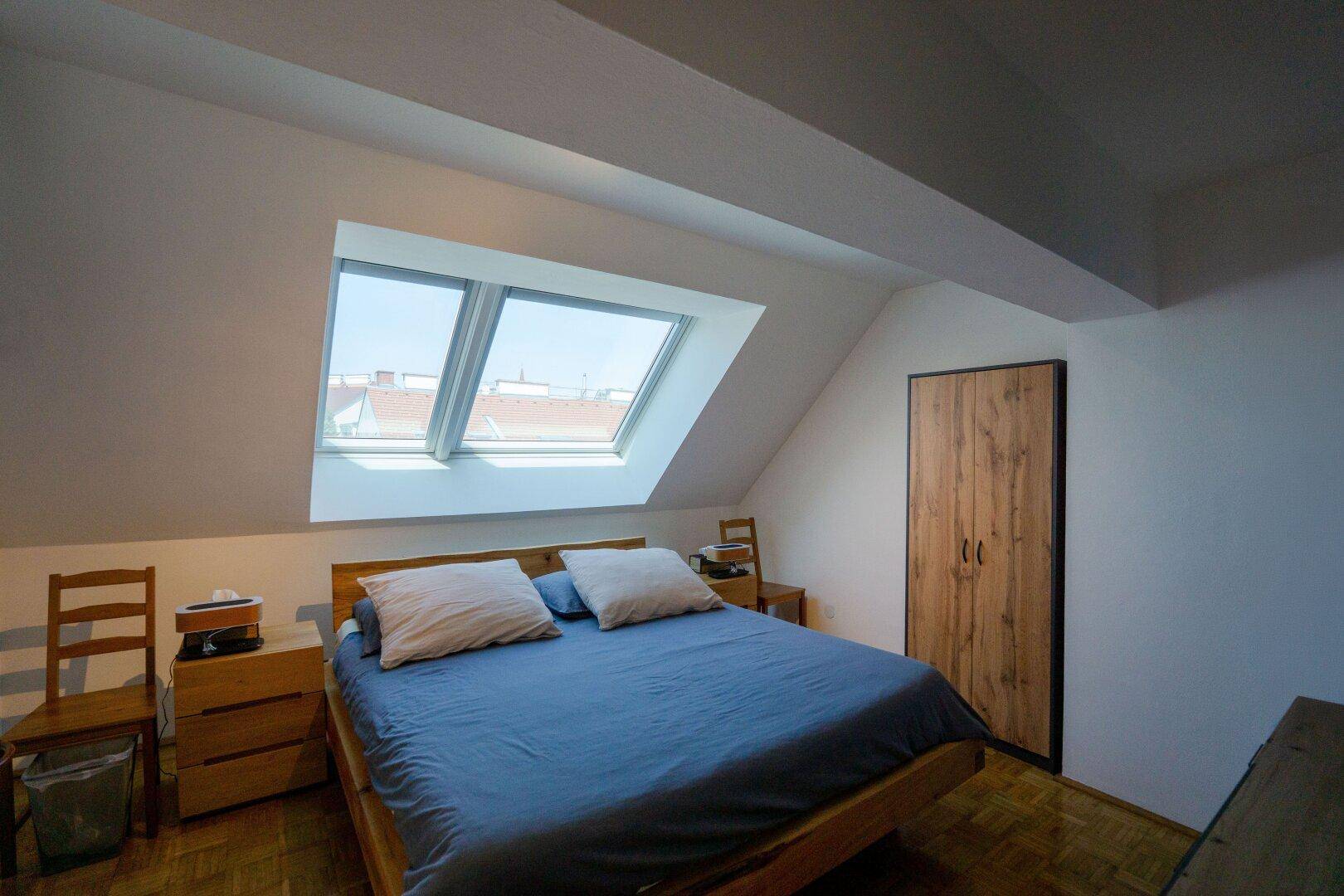 Gemütliches Schlafzimmer im Dachgeschoss mit Doppelbett, Holzboden und Dachfenstern.