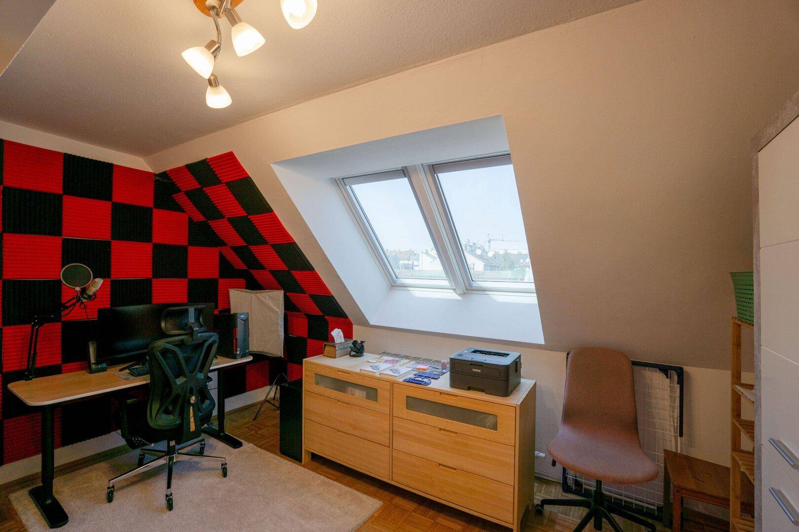 Kreatives Arbeitszimmer im Dachgeschoss mit Schreibtisch, Dachfenstern und Schallschutzplatten.
