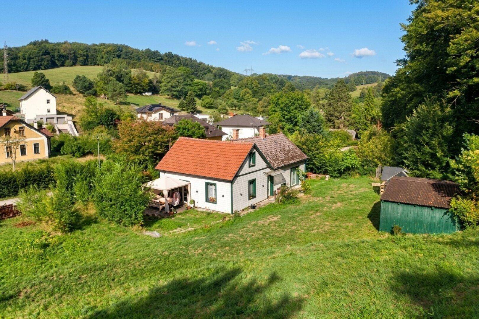 Weitläufige Ansicht des Landhauses in einer malerischen ländlichen Umgebung mit weiteren Häusern.