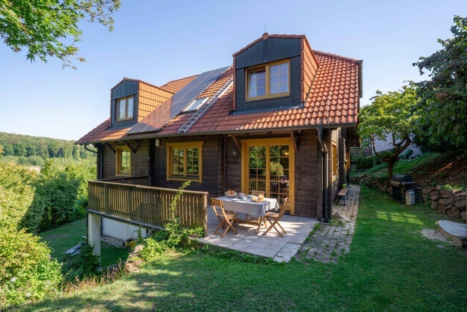 Gemütliche Terrasse mit Esstisch und Stühlen, umgeben von üppigem Grün und weitem Blick in die Natur.