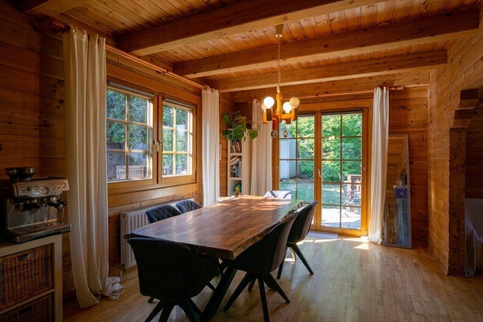 Gemütlicher Essbereich mit großem Holztisch, Holzbalkendecke und direktem Zugang zur Terrasse.