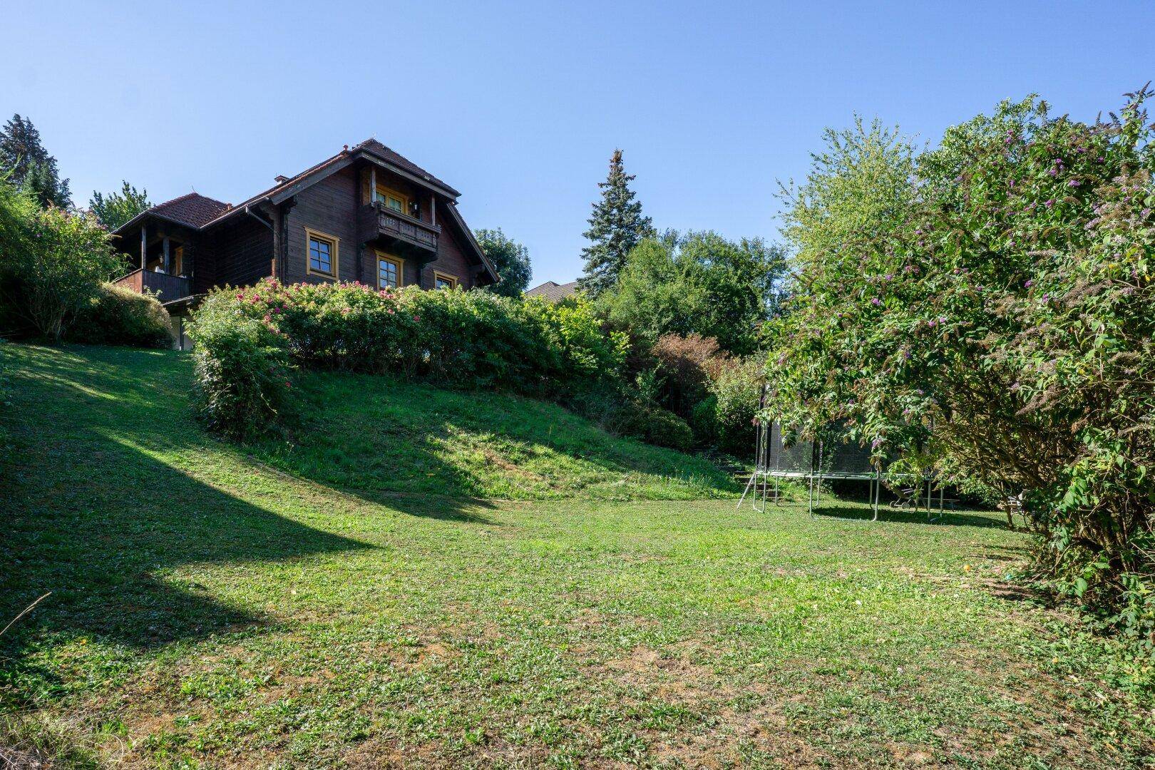 Großer, sonniger Gartenbereich mit Rasenfläche und einem Trampolin für Freizeitaktivitäten im Freien.