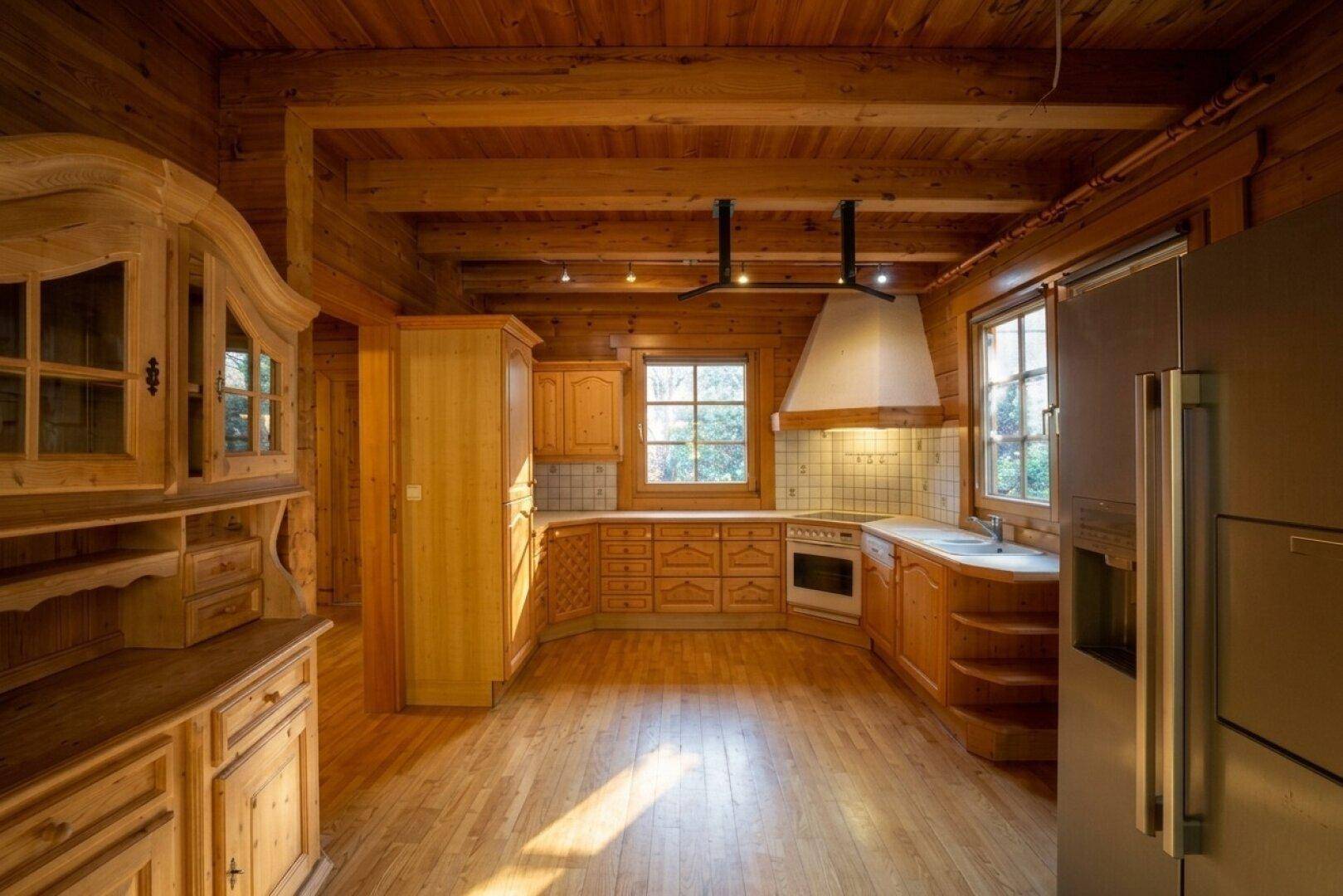 Rustikale Holzküche mit Einbauschränken, Holzbalkendecke und viel natürlichem Licht durch die Fenster.