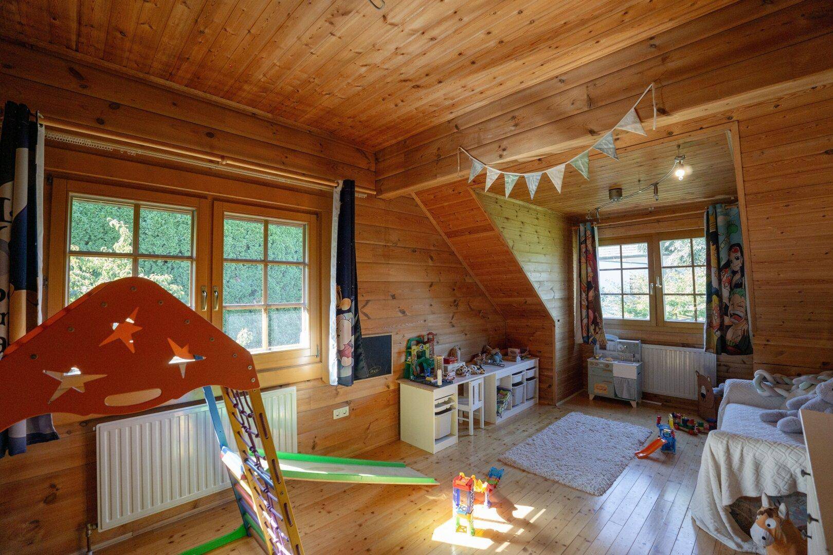 Kinderzimmer mit Holzverkleidung, Holzboden und verspielter Dekoration unter gemütlichen Dachschrägen.