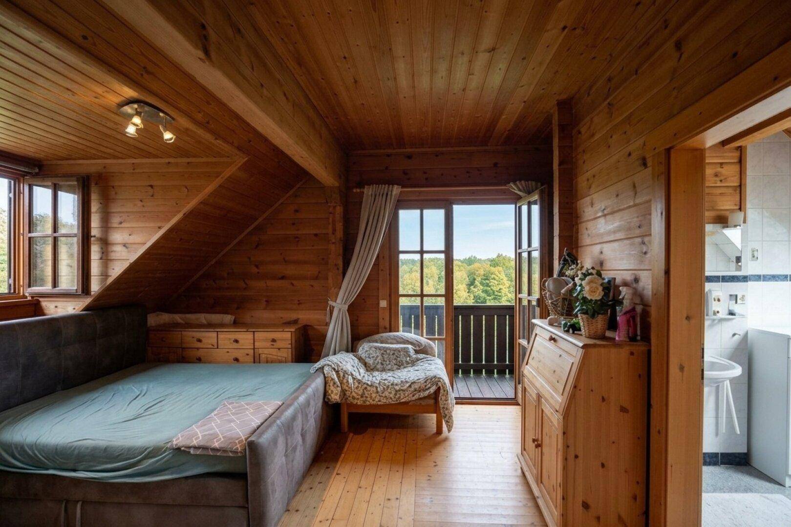 Schlafzimmer mit Holzboden, Holzverkleidung und direktem Zugang zu einem Balkon mit Aussicht.