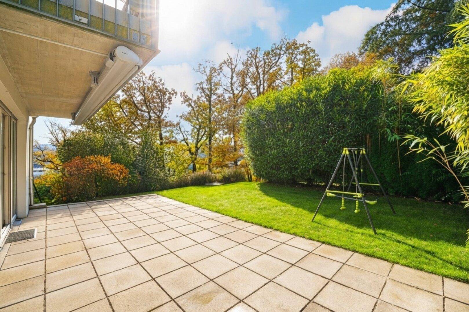 Sonnige Terrasse mit großzügiger Rasenfläche und Blick ins Grüne.