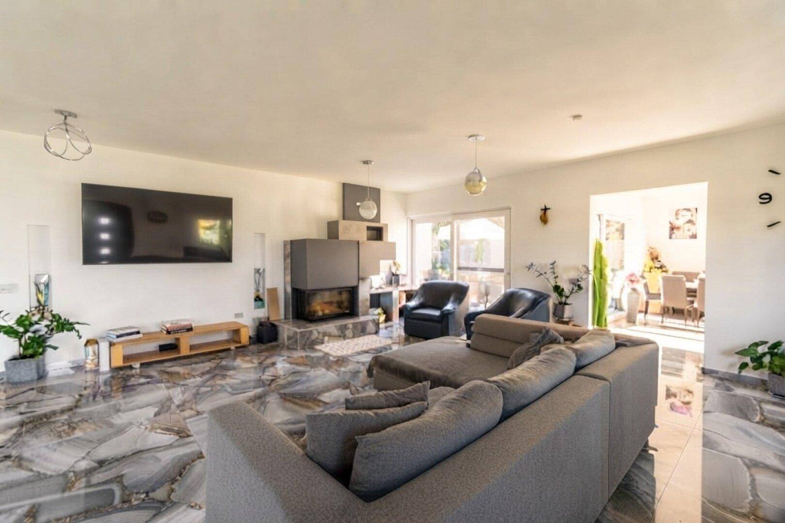 Geräumiges Wohnzimmer mit modernem Kamin, großem Sofa und glänzenden Fliesenböden.