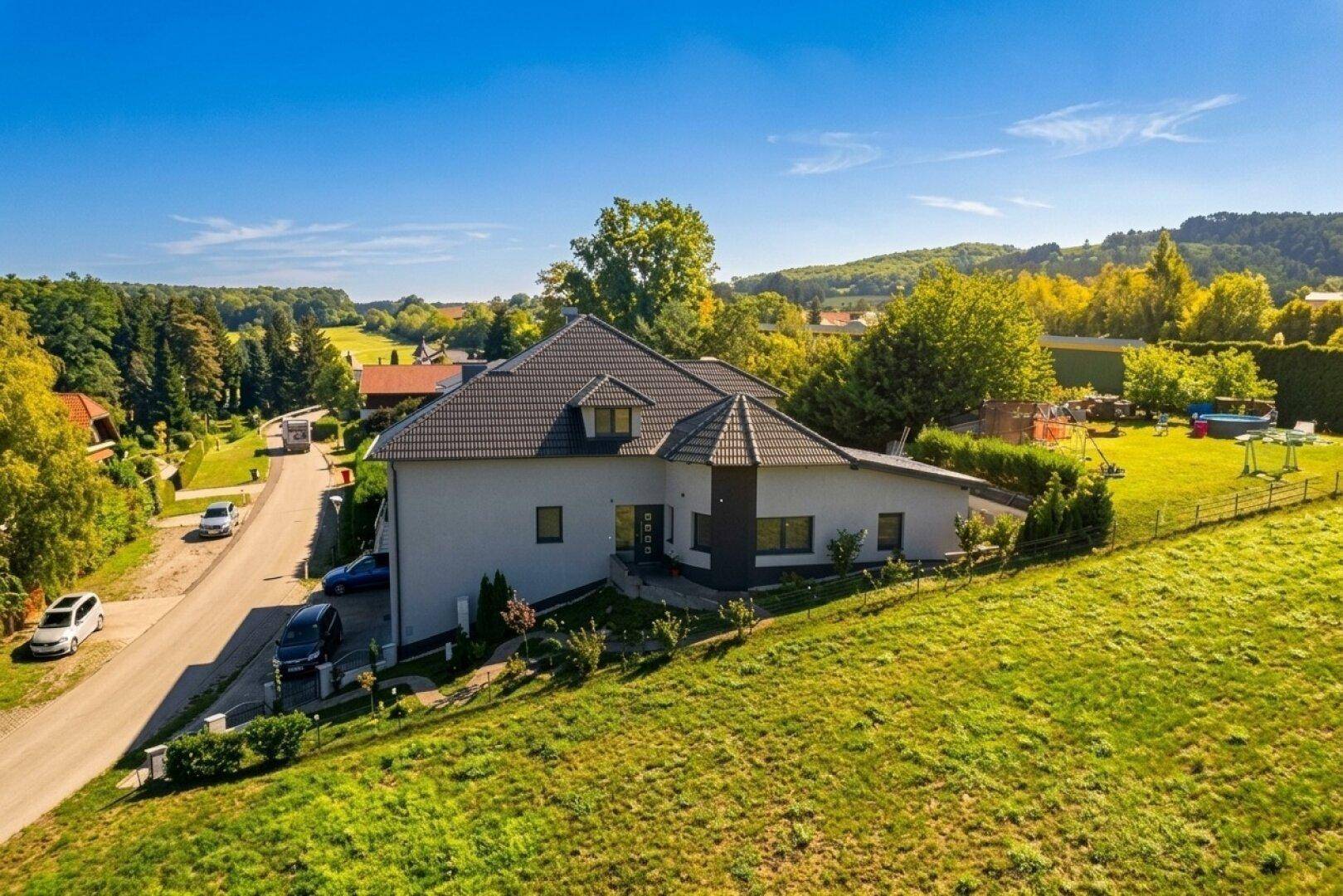 Weitläufige Ansicht des modernen Einfamilienhauses mit großem Garten und ländlichem Ausblick.