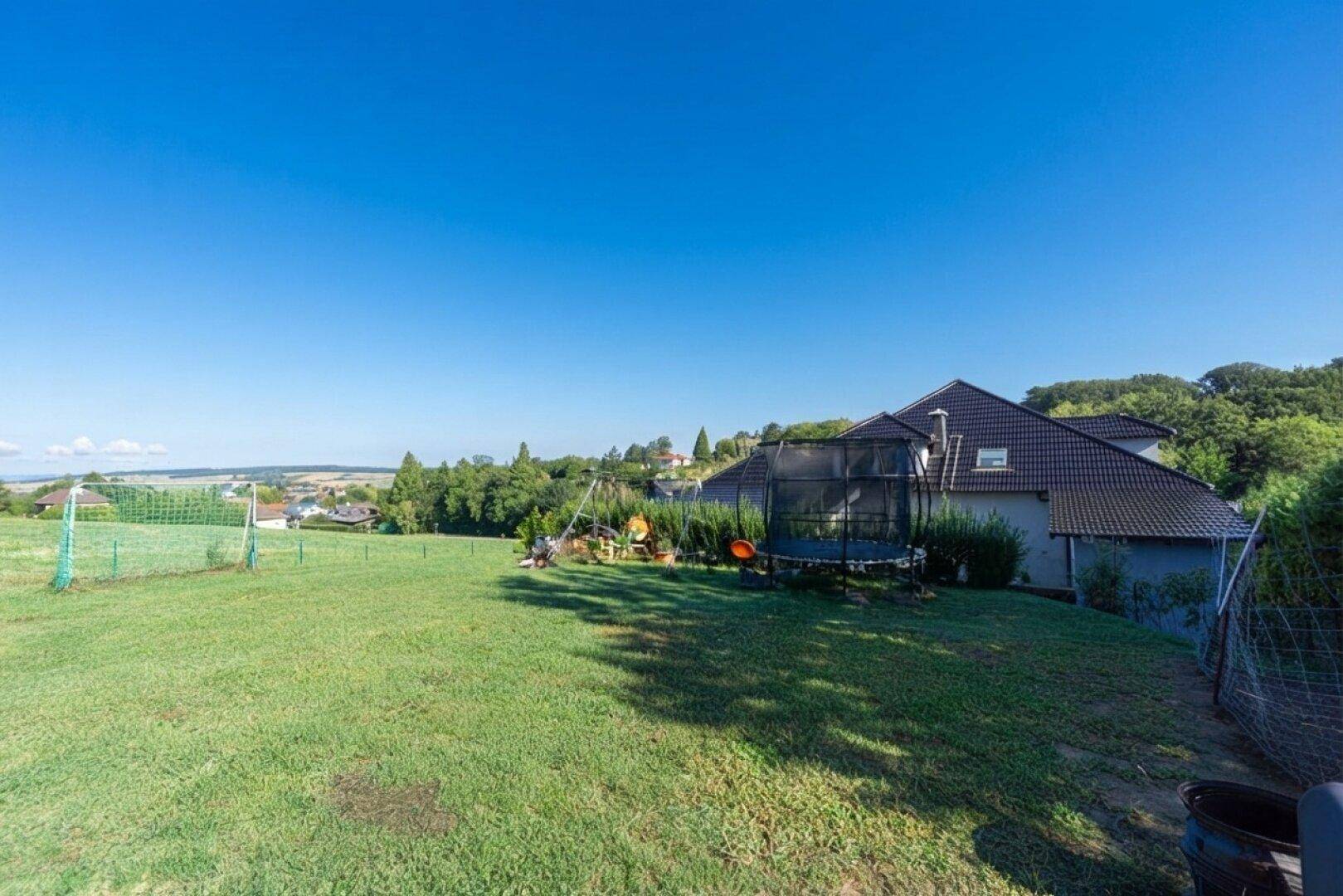 Großer Garten mit Rasenfläche, Trampolin und Spielgeräten, ideal für Familienaktivitäten.