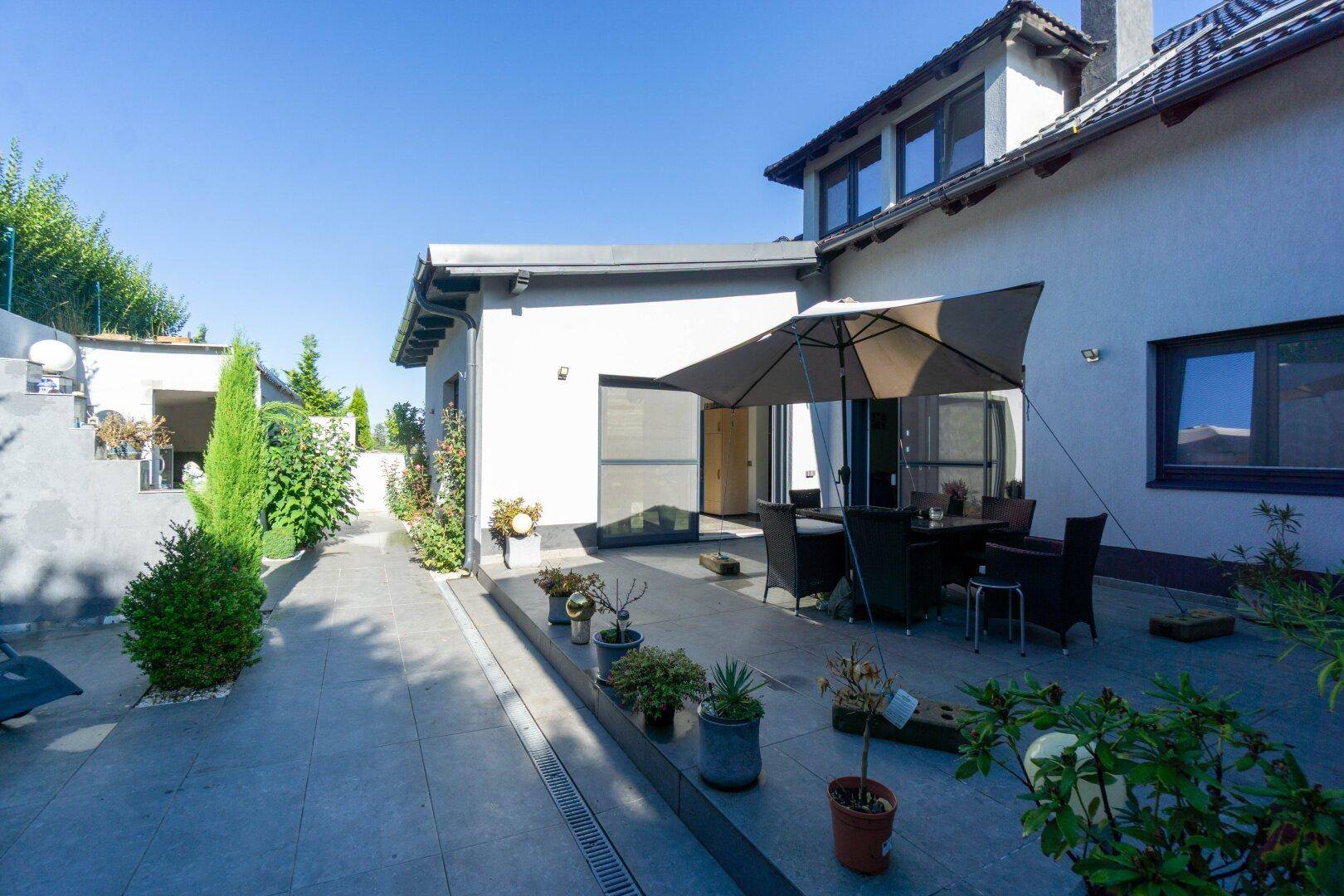 Geräumige Terrasse mit Outdoor-Sitzbereich und Sonnenschirm, ideal für Entspannung im Freien.