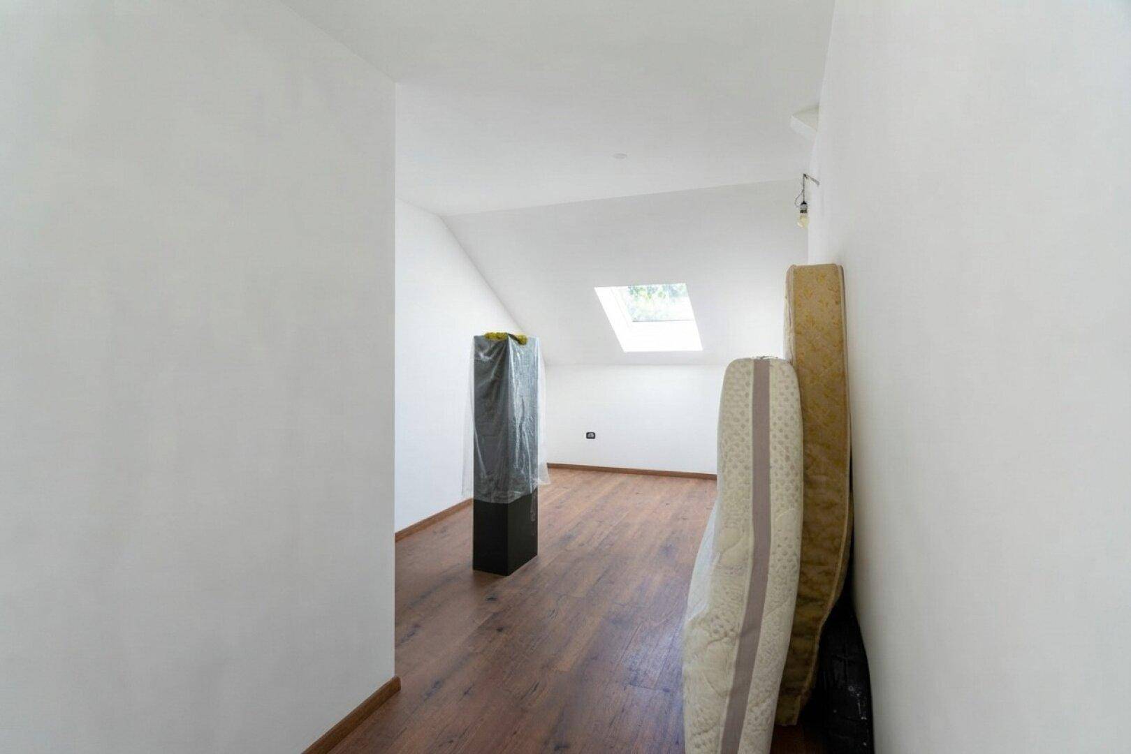 Heller Dachgeschossflur mit Holzboden und Dachfenster, ideal als zusätzlicher Stauraum.