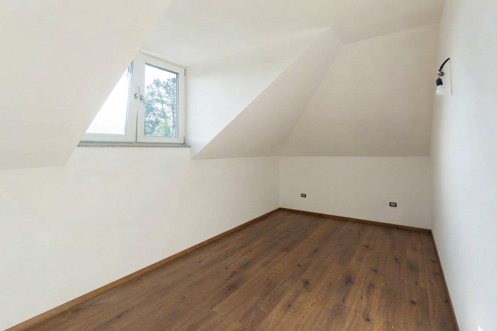 Helles Dachgeschosszimmer mit Holzboden und Fenster, bereit für individuelle Gestaltung.