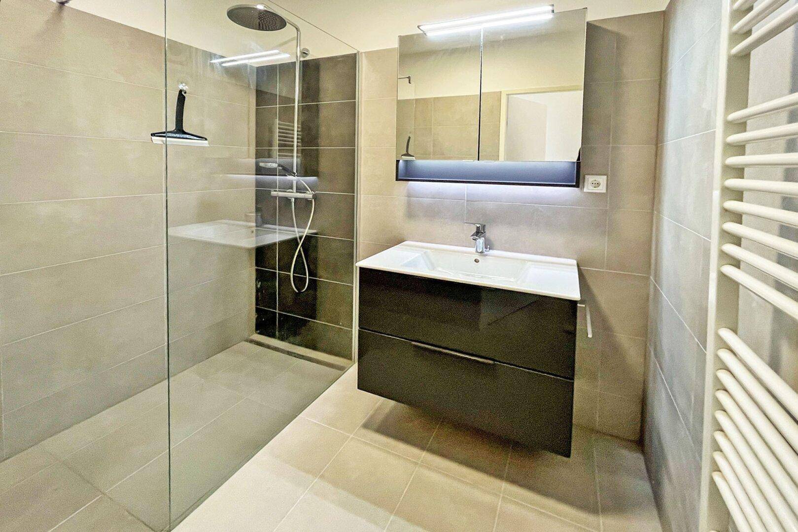 Modernes Badezimmer mit begehbarer Dusche, Waschtischunterschrank und Handtuchheizkörper.