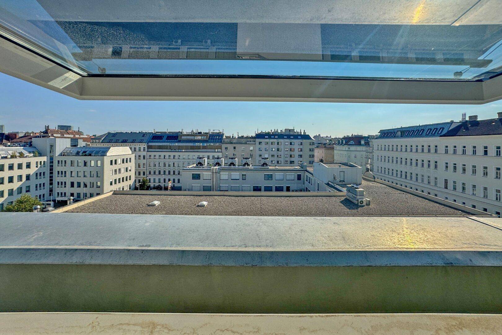 Weitblick über die Dächer der Stadt von einem geöffneten Dachfenster aus.