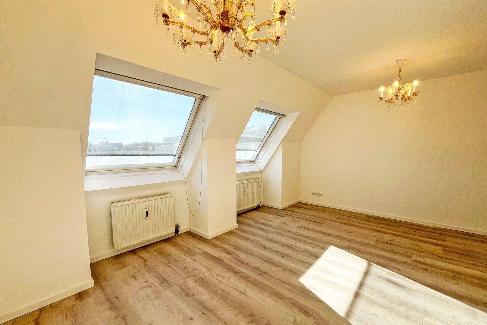 Dachgeschosszimmer mit Laminatboden, Heizkörpern und zwei Dachfenstern für viel Licht.