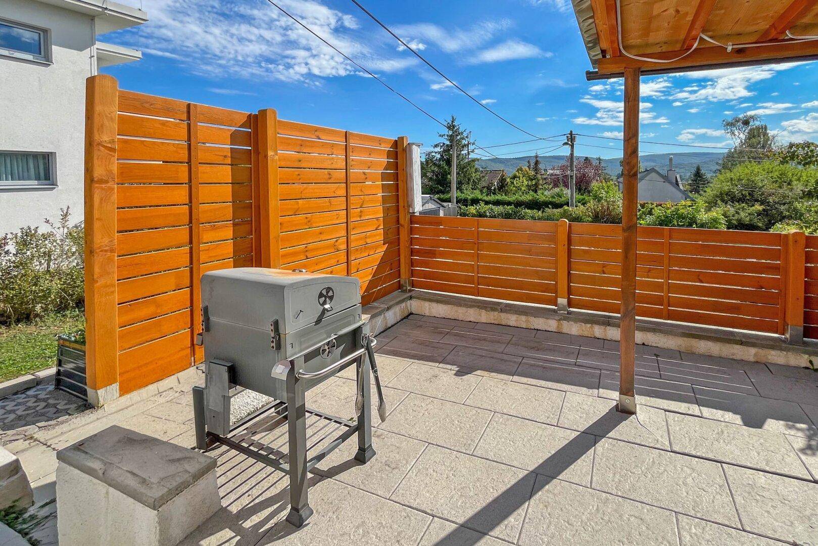 Geräumige Terrasse mit Holzverkleidung und einem Grill für gemütliche Abende.