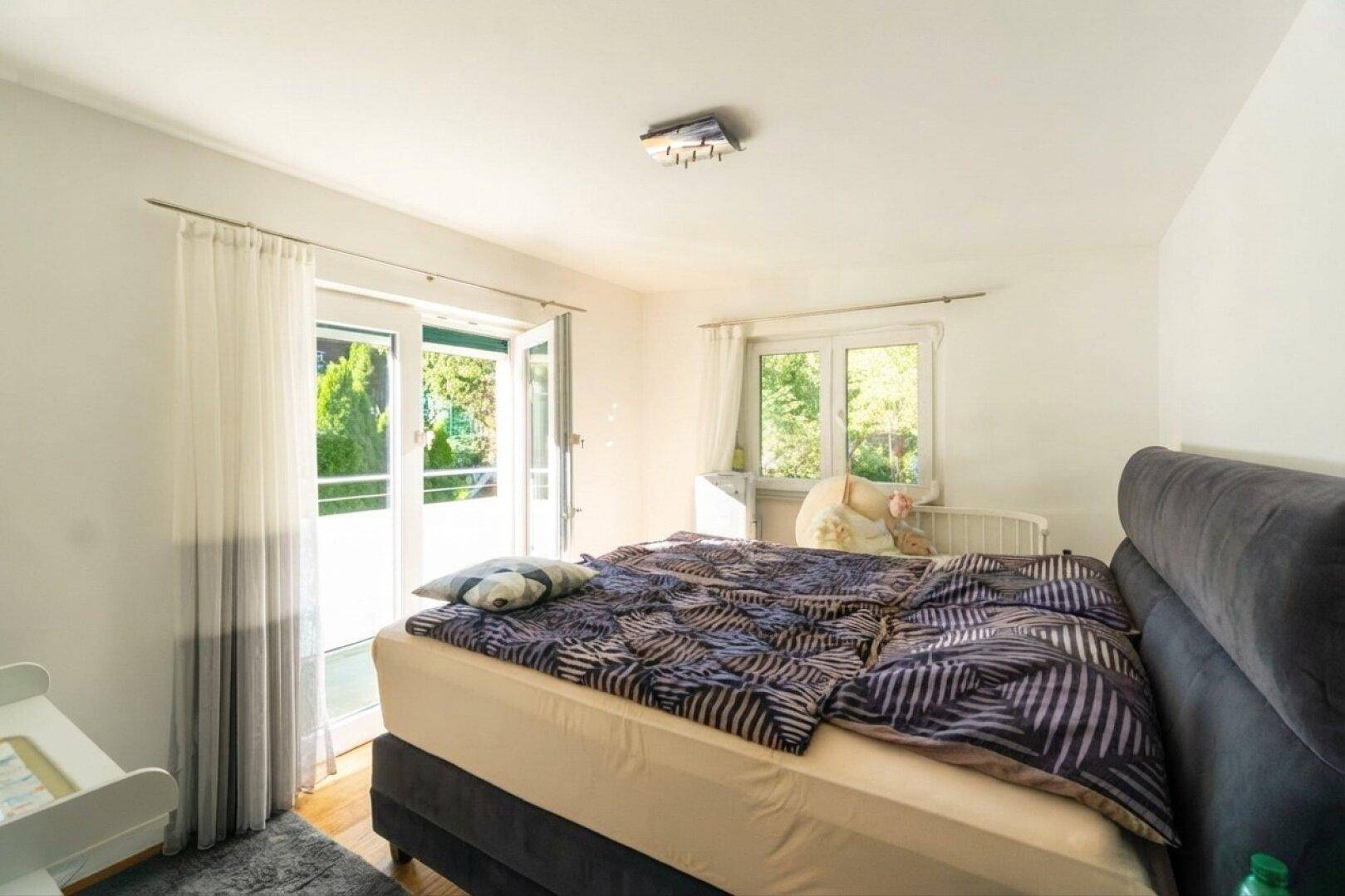 Schlafzimmer mit Doppelbett, Holzboden und direktem Zugang zu einem Balkon.