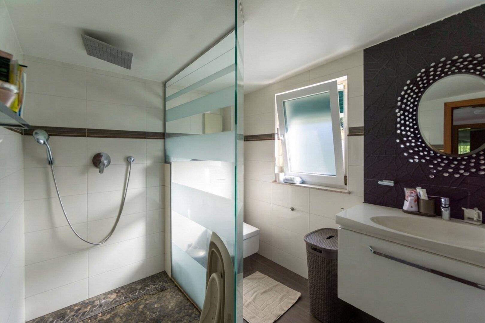 Modernes Badezimmer mit Duschkabine, Waschbecken und Fenster für Tageslicht.