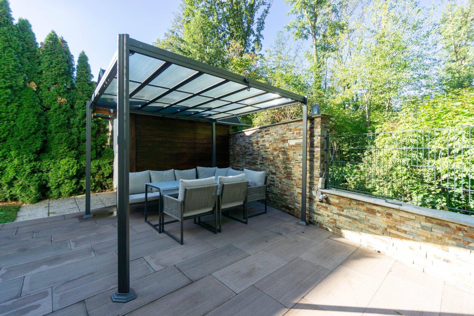 Überdachte Terrasse mit Sitzgelegenheiten und Steinwand, perfekt für entspannte Stunden im Freien.