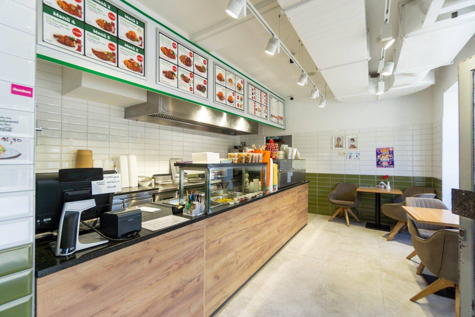 Moderne Theke und Essbereich eines Schnellrestaurants mit Fliesenwänden und Holzverkleidung.