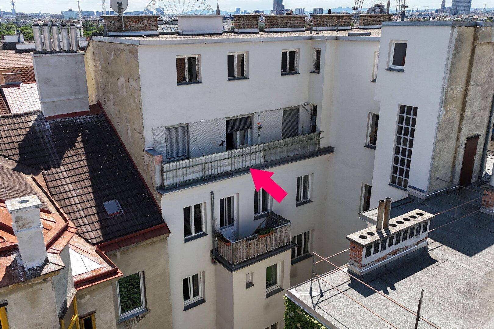 Dachterrassenbereich eines Wohngebäudes mit Glasgeländer und Blick auf die Stadt.