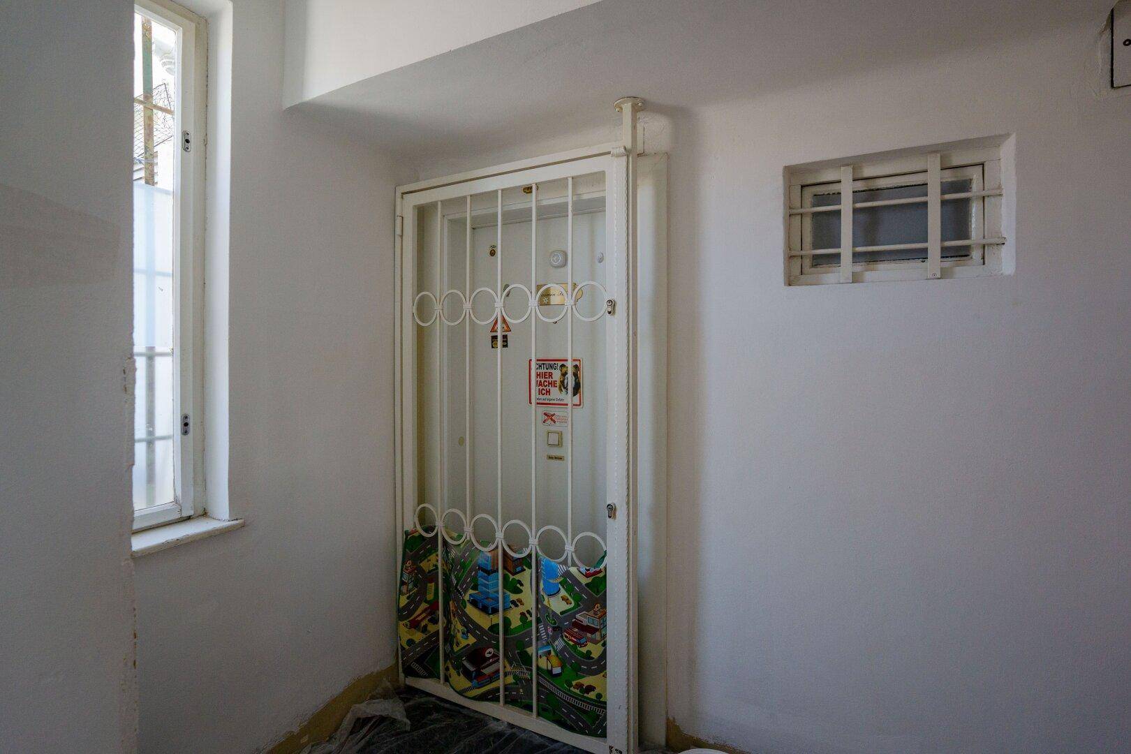 Aufzug mit Gittertür und spielerischer Dekoration im Treppenhaus eines Mehrfamilienhauses.