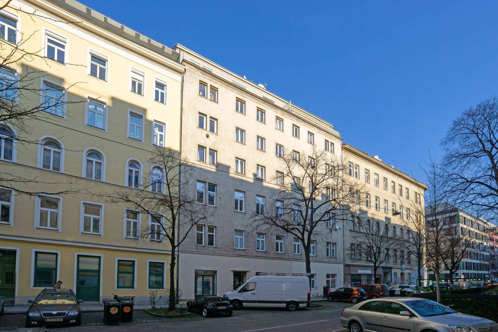 Mehrstöckiges Wohngebäude mit klassischer Fassade und vielen Fenstern an einer städtischen Straße.