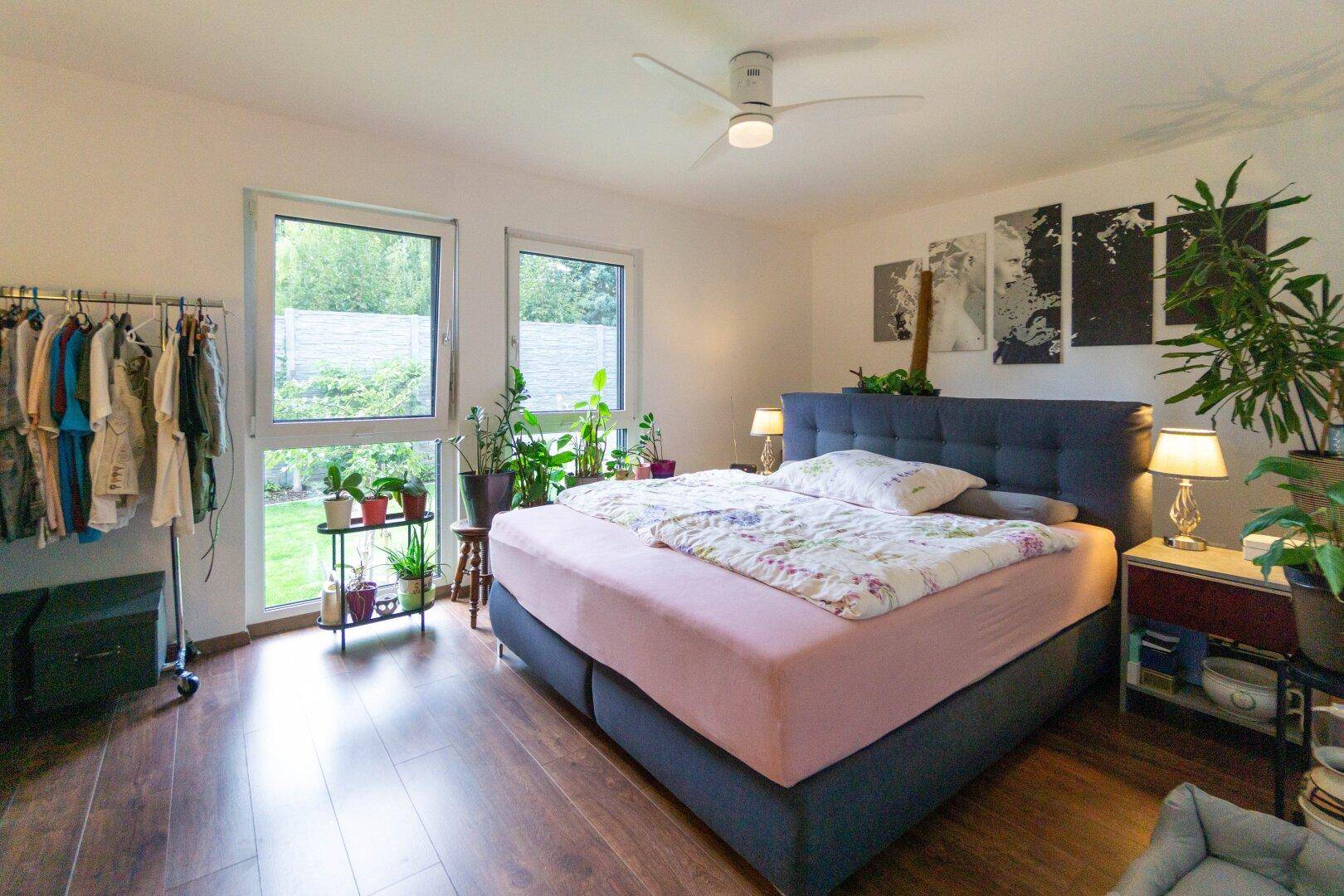 Helles Schlafzimmer mit großem Bett, Holzboden und direktem Zugang zum Garten.
