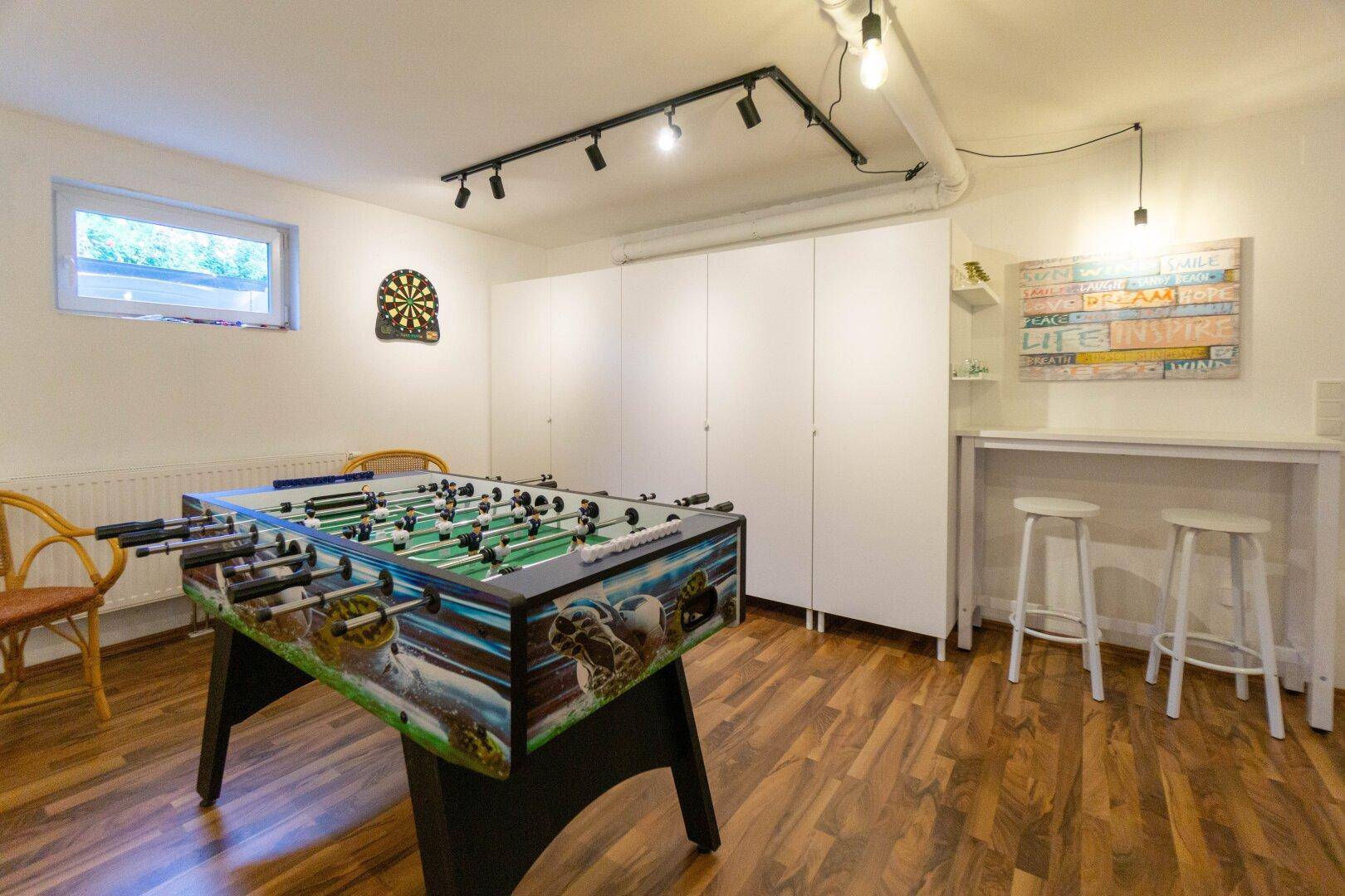 Unterhaltsamer Spielraum im Keller mit Tischfußball, Dartscheibe und Bar.