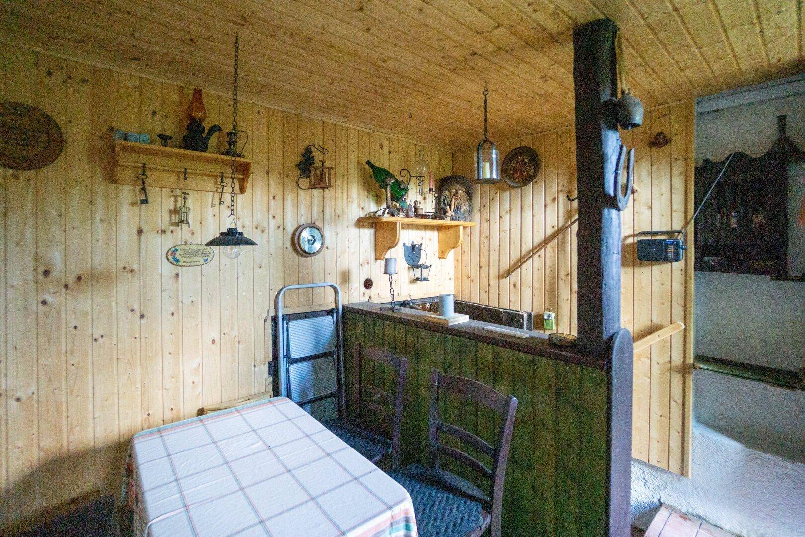 Rustikaler Barbereich im Keller mit Holzverkleidung, Theke und traditioneller Dekoration.