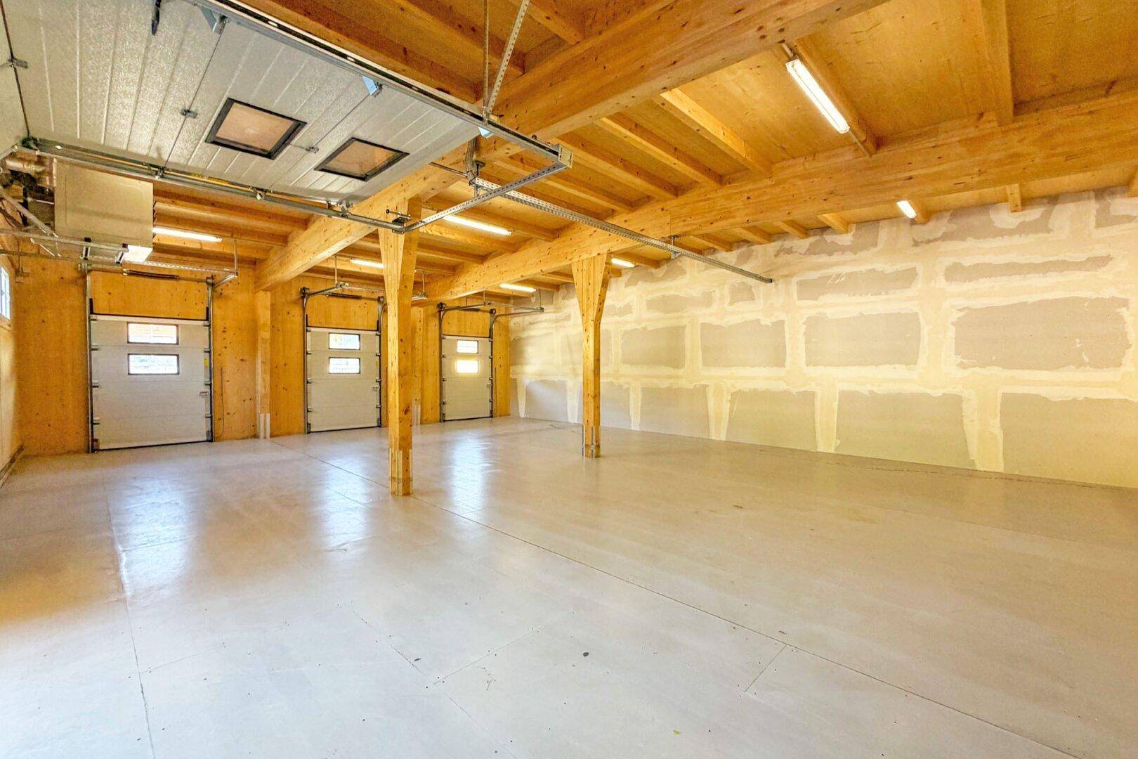 Weitläufige Lagerhalle mit Holzbalken und Betonboden, bereit für verschiedene gewerbliche Nutzungen.