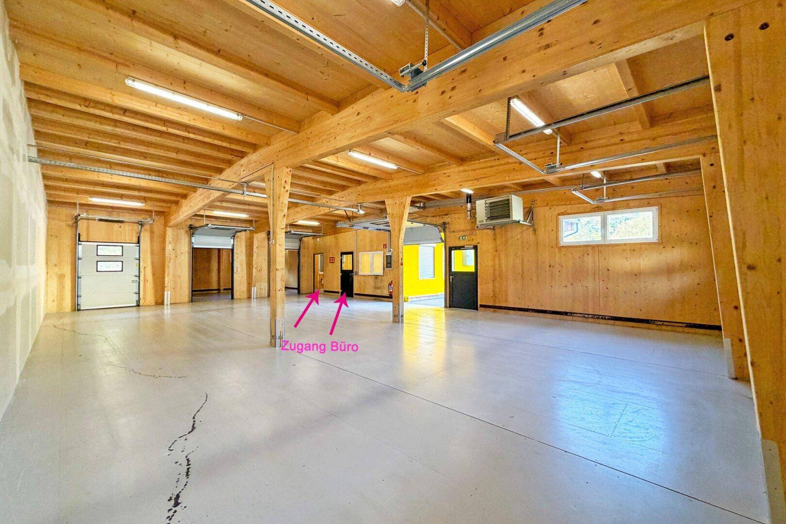 Lagerhalle mit Betonboden, Holzbalken und Zugang zum Bürobereich, ideal für kombinierte Nutzung.