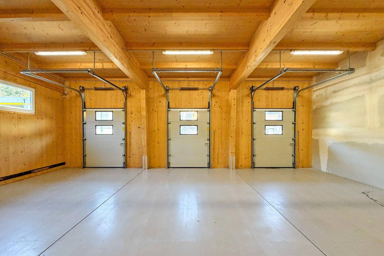 Innenansicht der Lagerhalle mit drei großen Rolltoren und einer robusten Holzkonstruktion.