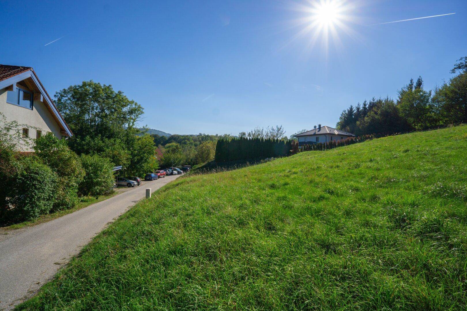 Sonniges Grundstück mit weitem Blick über die grüne Landschaft und angrenzender Straße, ideal für Naturliebhaber.