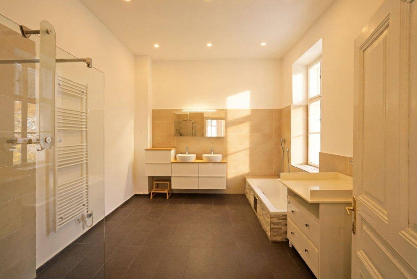 Modernes Badezimmer mit Doppelwaschbecken, Badewanne, Dusche und beheiztem Handtuchhalter.