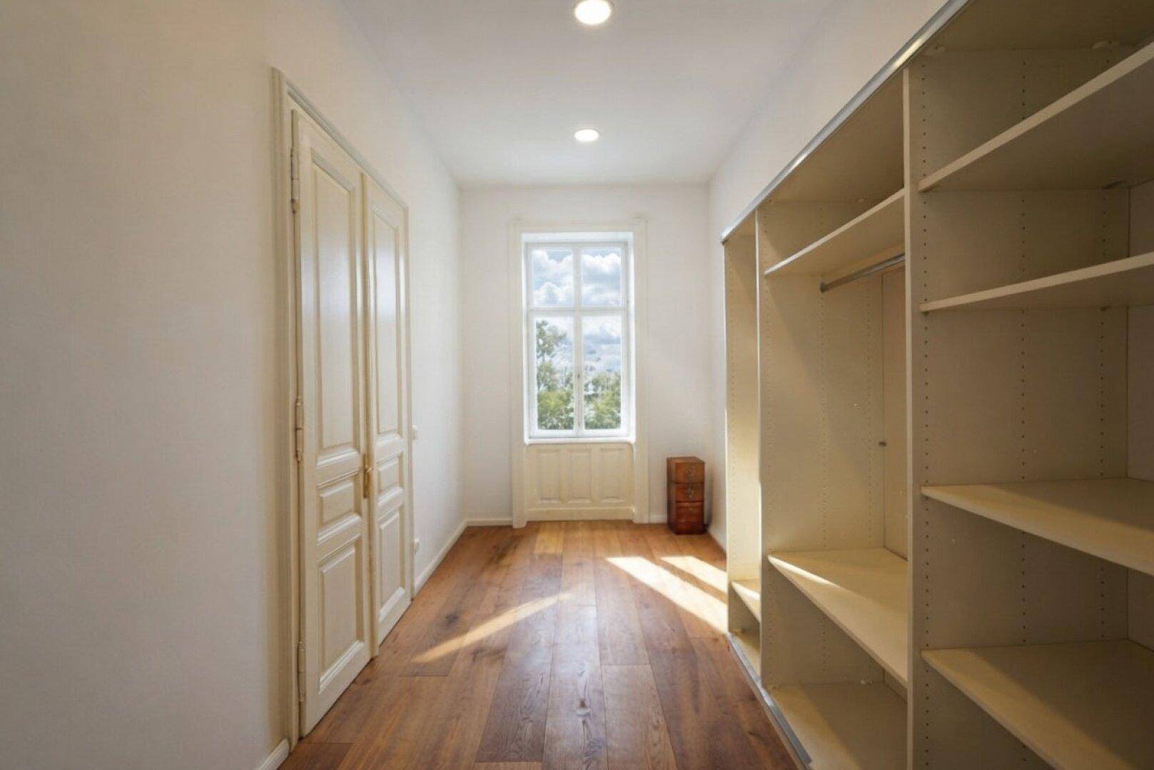 Geräumiger begehbarer Kleiderschrank mit Regalsystemen und Fenster für Tageslicht.
