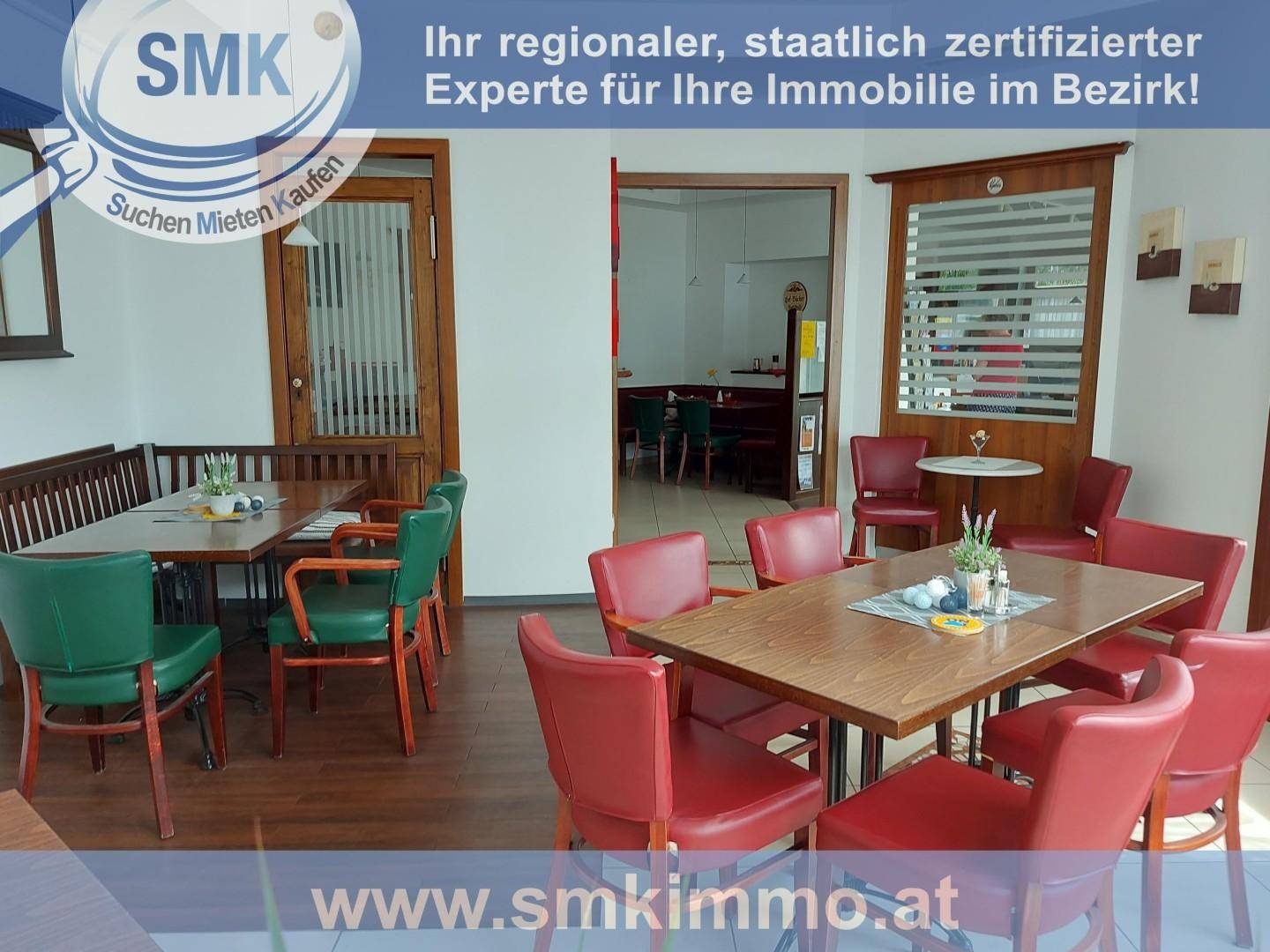 Innenansicht eines Cafés oder Restaurants mit Holztischen und roten sowie grünen Stühlen.