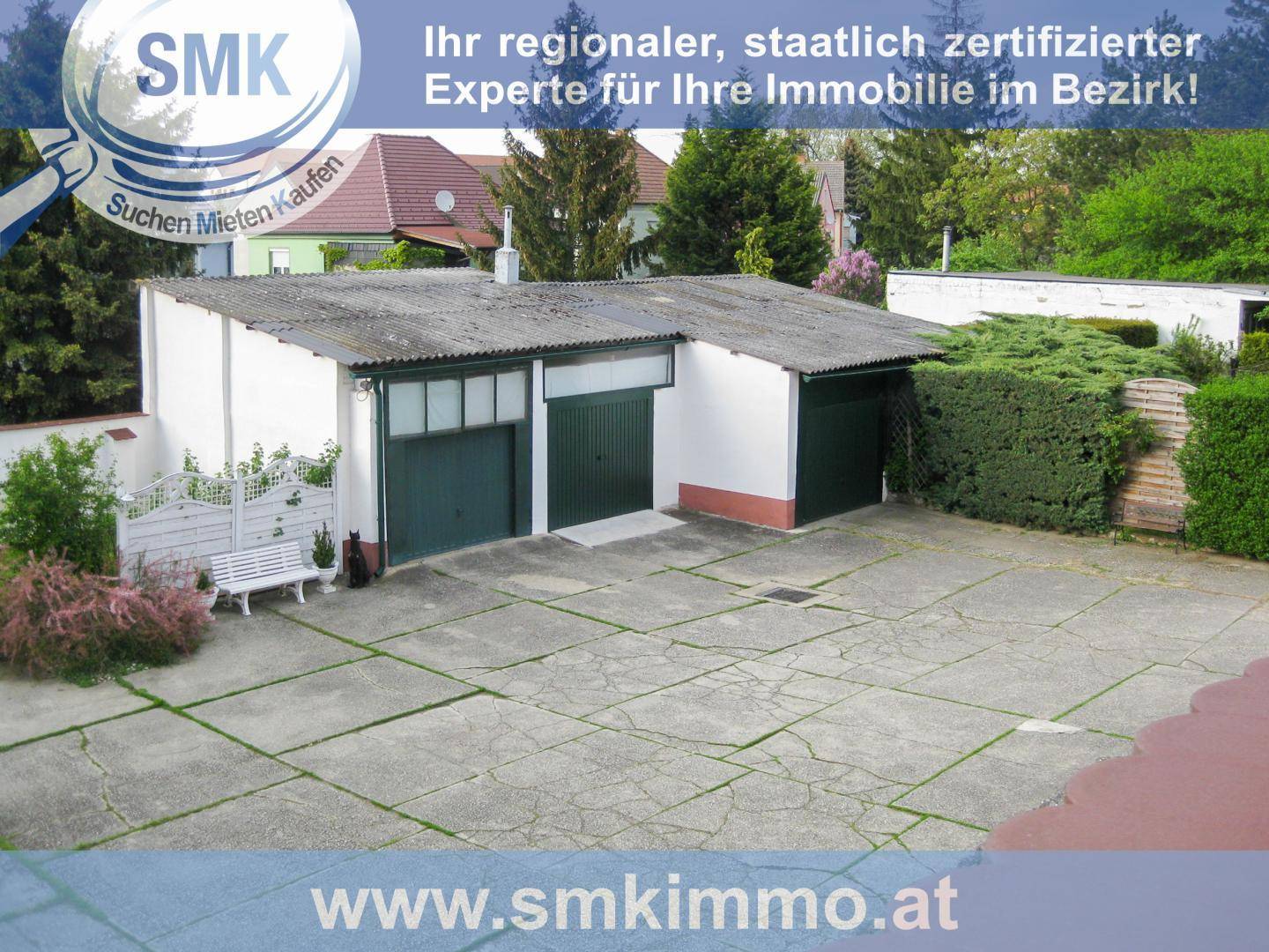 Übersicht des Garagengebäudes mit Zufahrt, Hecke und umliegender Fläche.
