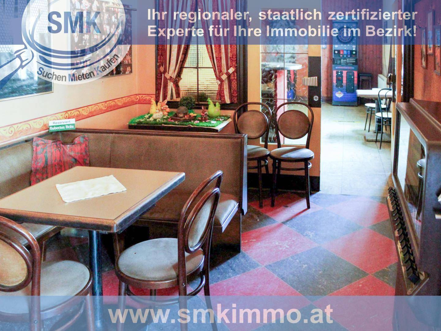 Sitzbereich in einem Lokal mit Tischen, Stühlen und einer gepolsterten Bank.