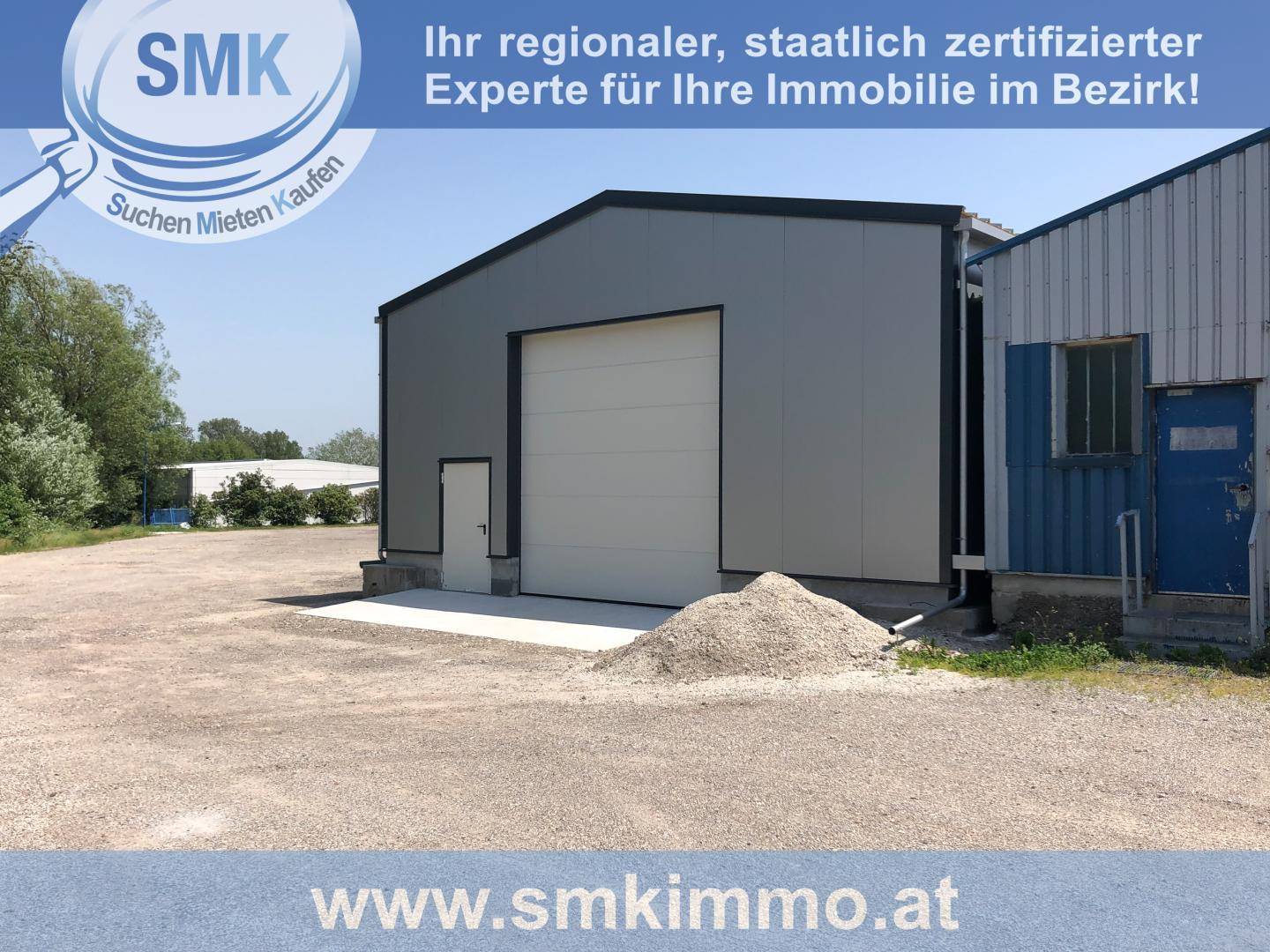 Außenansicht eines modernen Industriegebäudes mit großem Rolltor und kleinerer Eingangstür.