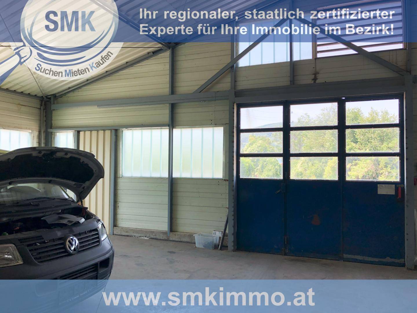 Innenansicht einer Werkstatt oder Lagerhalle mit einem Fahrzeug und großen Fenstern.