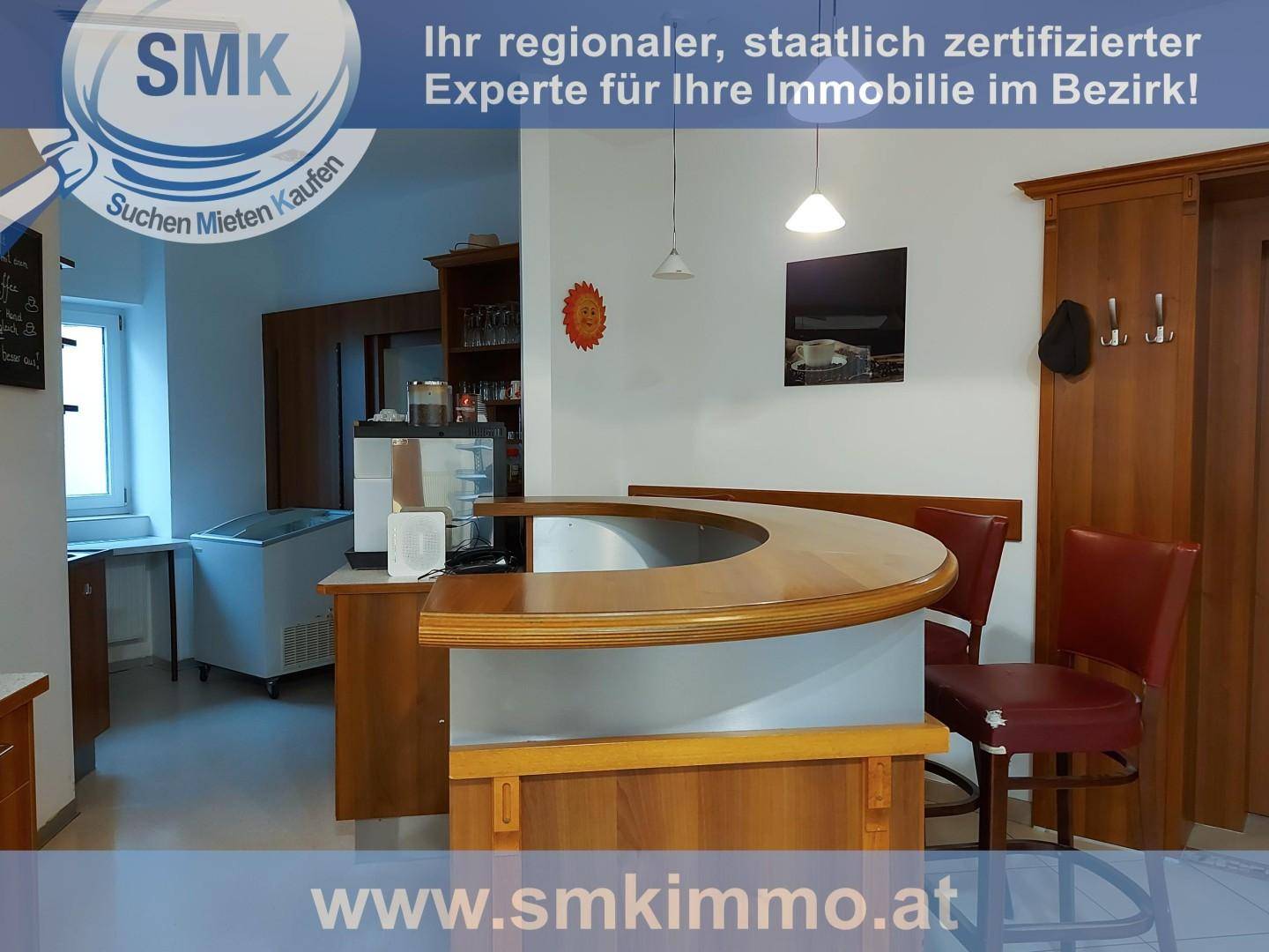 Thekenbereich eines Cafés oder einer Bäckerei mit Holztheke, Kühlvitrine und Regalen im Hintergrund.