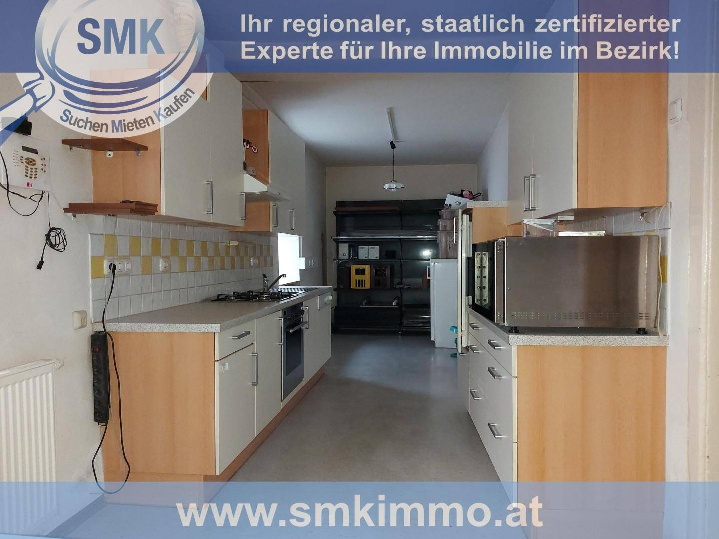Gewerbliche Küche mit Arbeitsflächen, Gasherd und Regalen für Lagerung im hinteren Bereich.