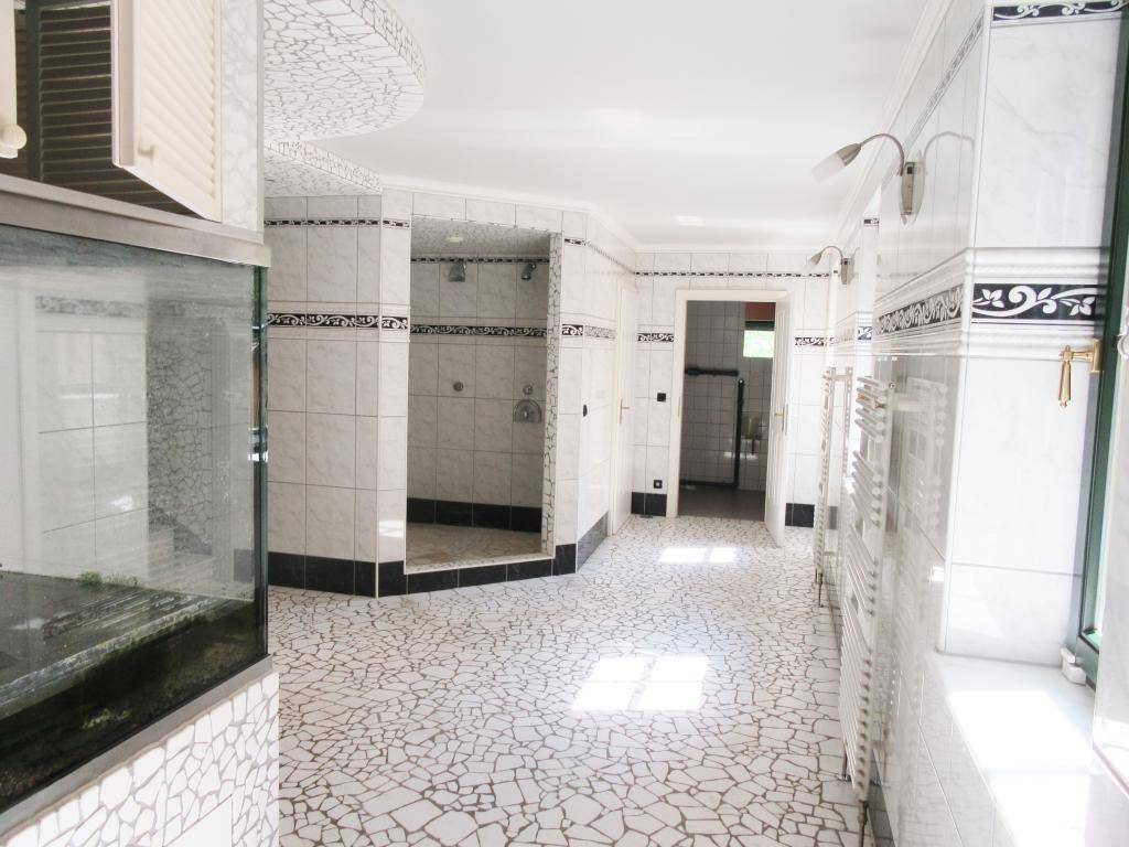 Spa-ähnlicher Bereich mit mehreren Duschkabinen und dekorativem Mosaikboden, hell und geräumig.