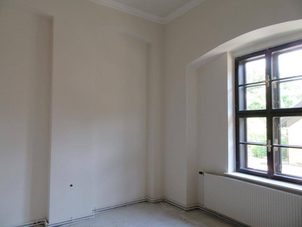 Leerer Raum mit einem großen Fenster und Heizkörper, ideal für individuelle Gestaltung.